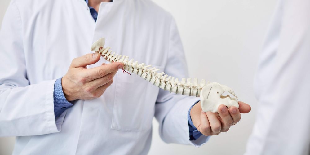 Ein Arzt erklärt einer Patientin, wie die Wirbelsäulentherapie funktioniert.
