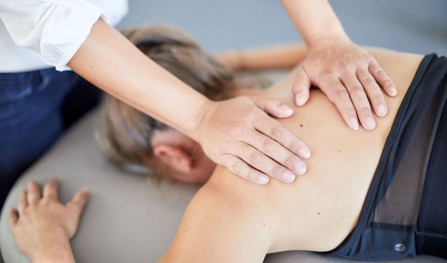 Eine Therapeutin führt bei der Physiotherapie eine Massage an einer Patientin durch.